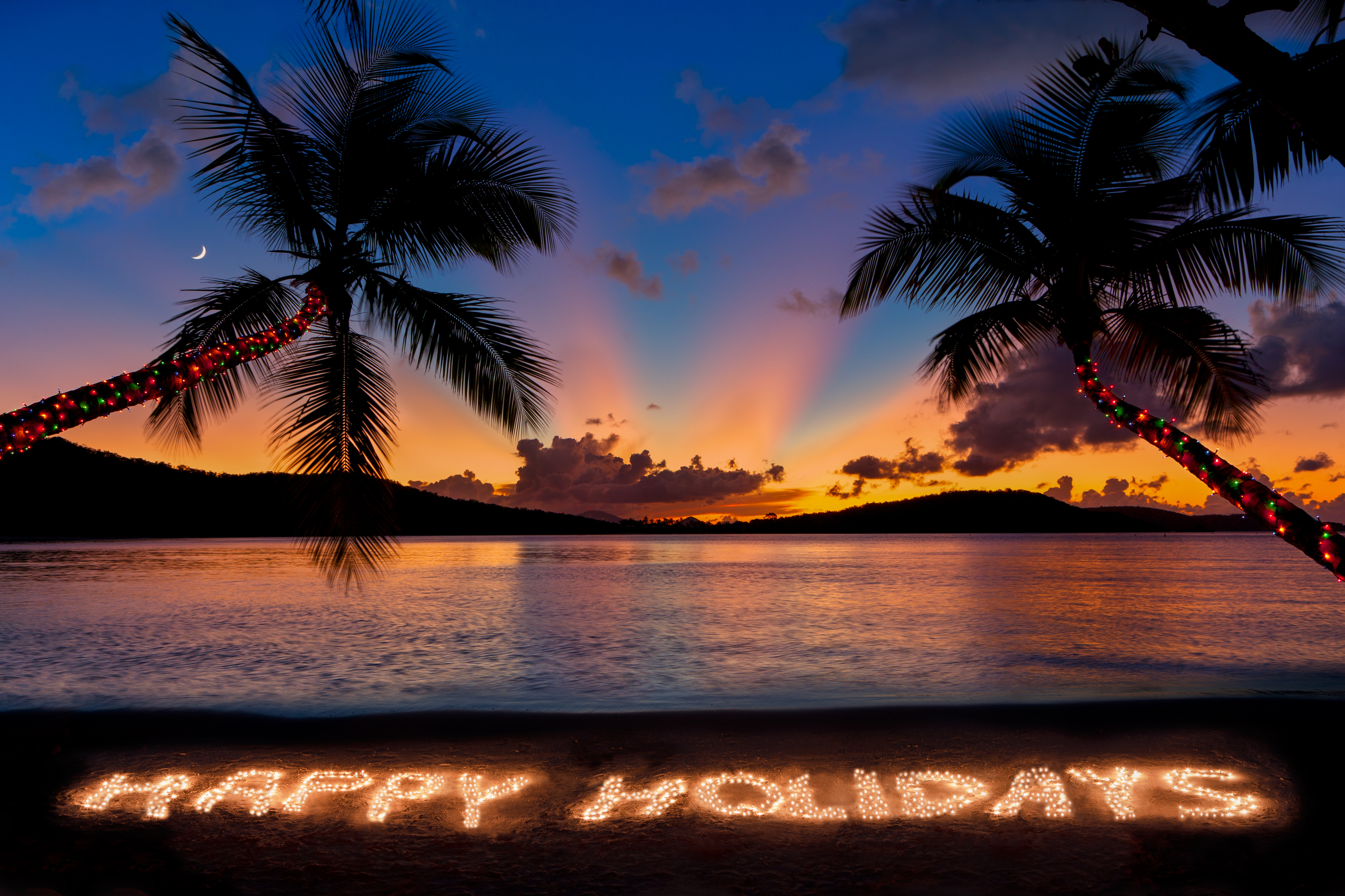 Happy Holidays made with Christmas lights at a tropical beach